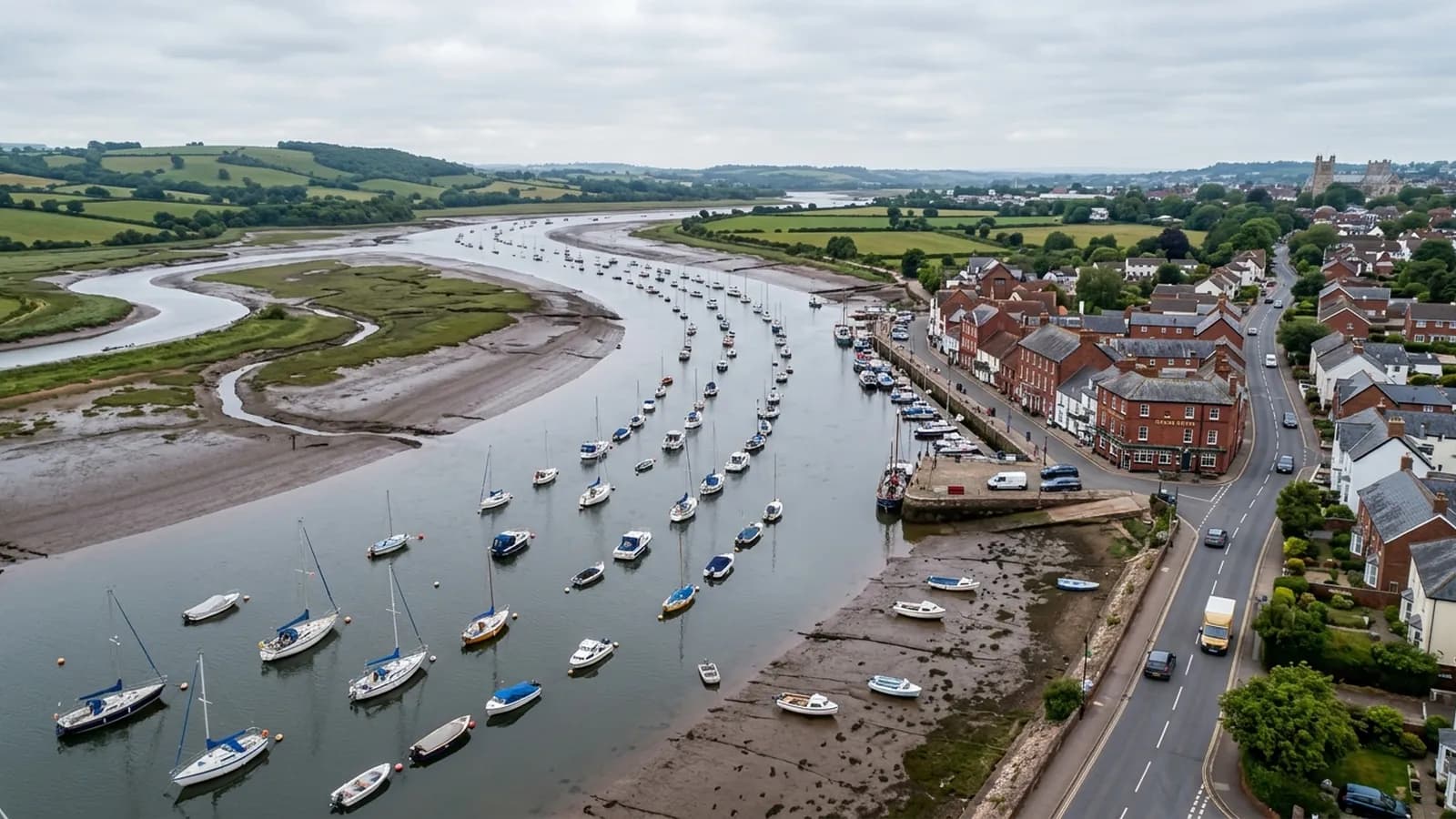 The Exe estuary at Topsham at half tide, moored boats and a quayside terrace with the road running back towards Exeter